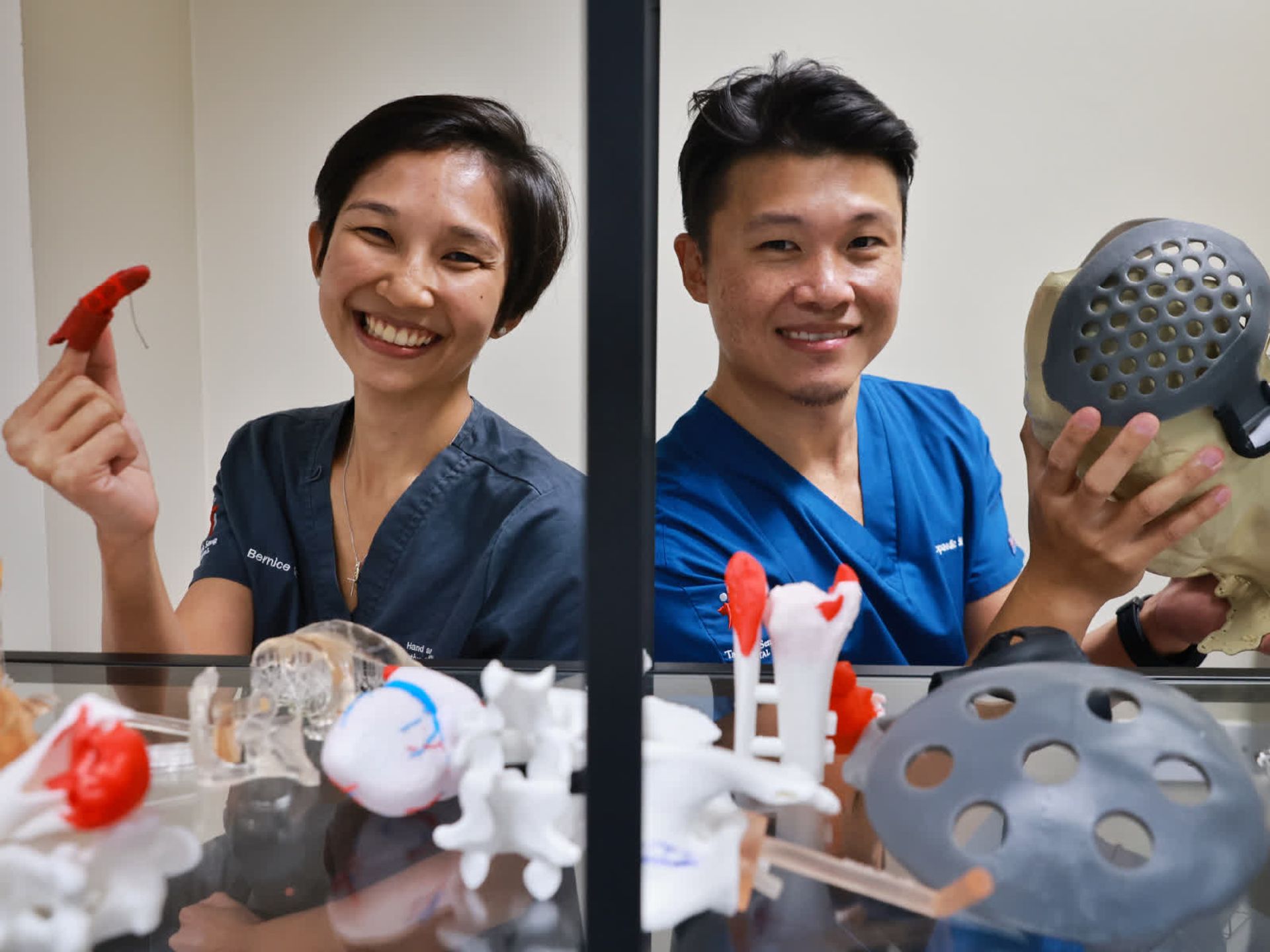 Tan Tock Seng Hospital's Dr Bernice Heng (left) with a 3D-printed finger prosthesis and Dr Michael Yam holding a cranial cap.