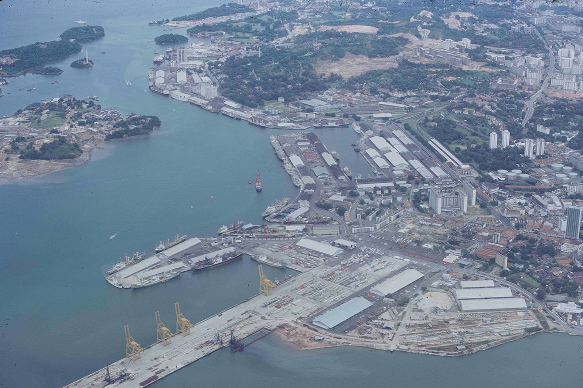 Photographed in the 1970s, Keppel Harbour, with Sentosa on the top left, is depicted before the extensive land reclamation that took place between 1979 and 1980. The cable car pylon is situated on the former Pulau Selegu, while Keppel Island – previously known as Pulau Hantu – had yet to be joined to the mainland.