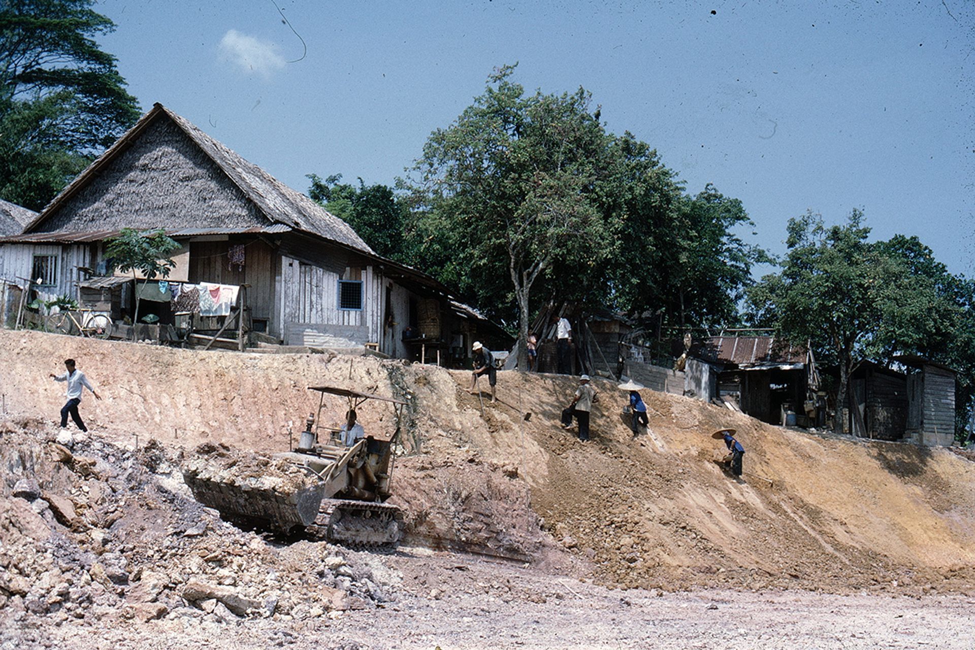 A hill in Queenstown being terraced for HDB flats around 1960. It was first roughly levelled by bulldozers, then men and women armed with cangkul (Malay for hoe) finished off the work.