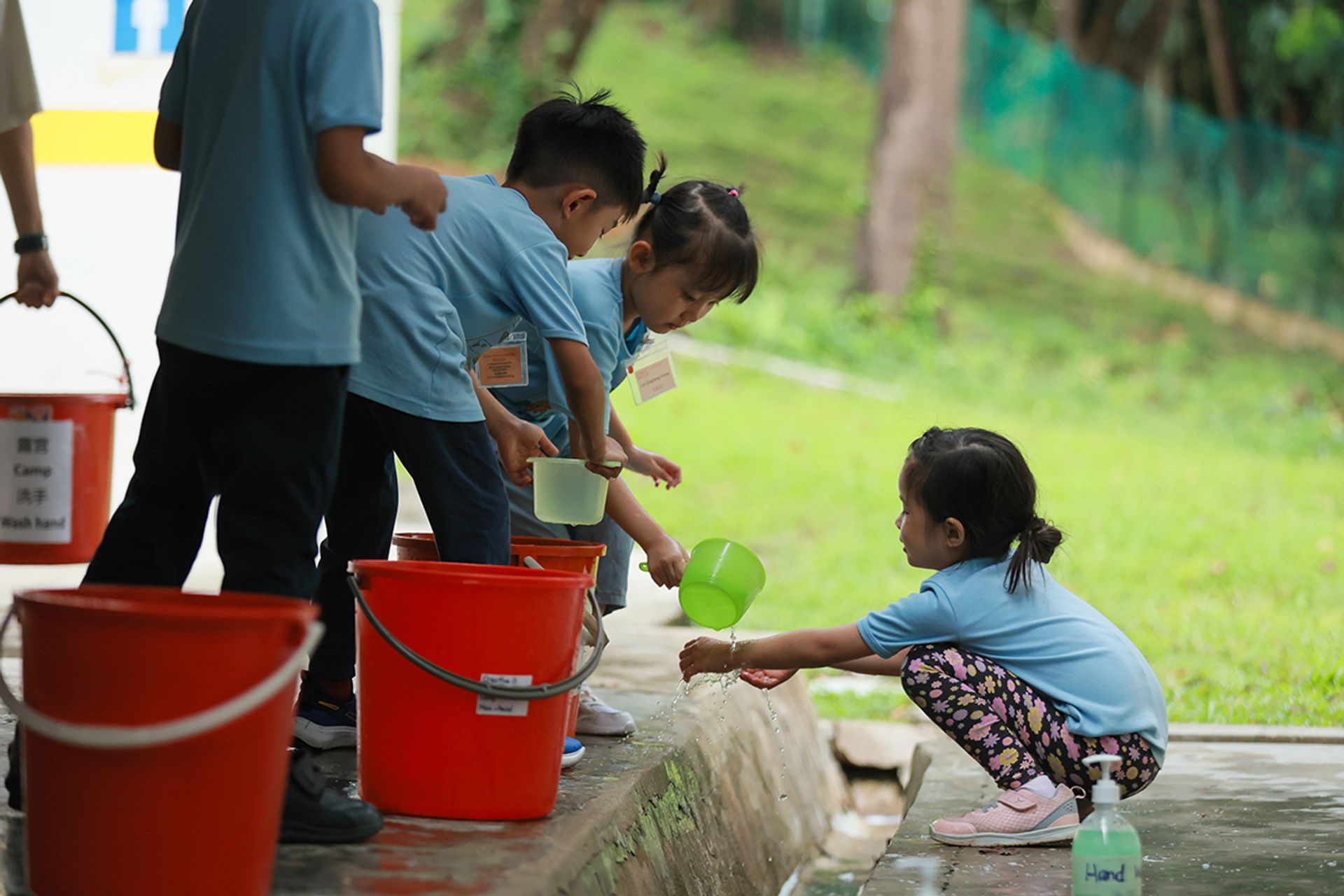 Children take turns to help one another to wash and clean up after preparing a meal at the campsite.