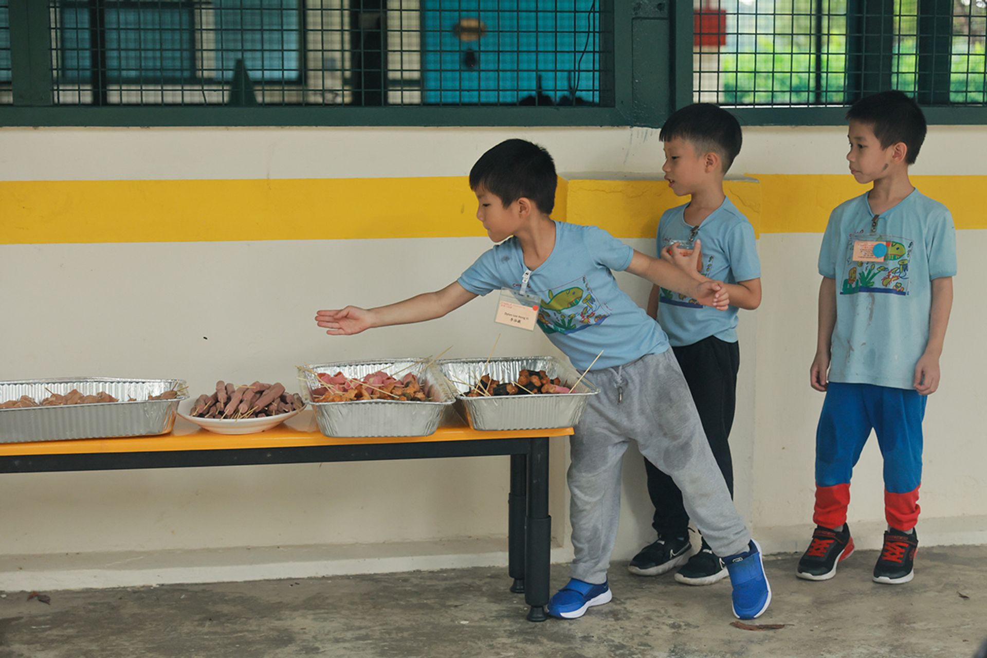 (From left) Dylan Lee, Jaiden Foo and Liam Loh guard the barbecued food from flies.