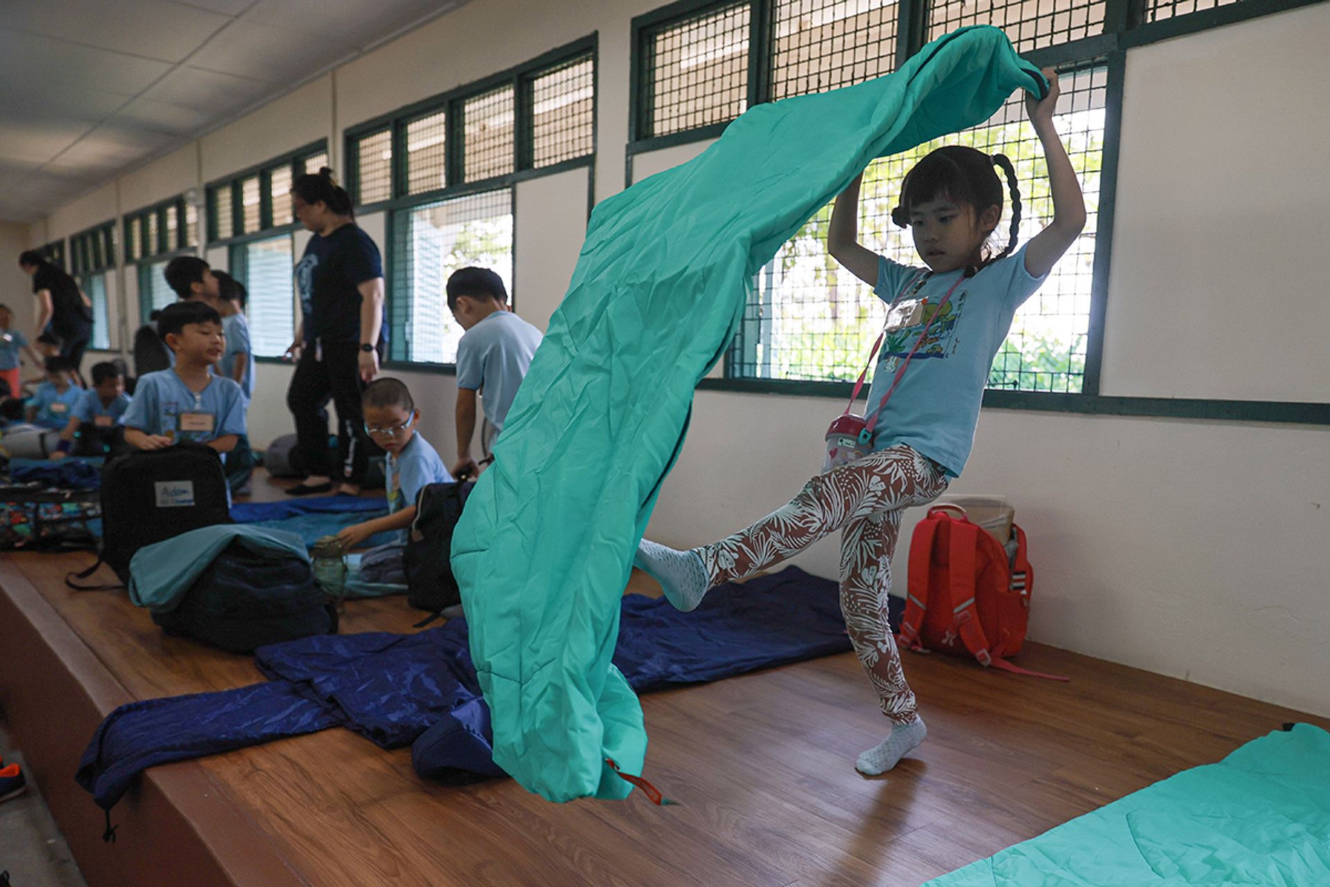 Huang Xinyi prepares her sleeping bag. As the lodge has no air-conditioning, the children sleep under ceiling fans, which are supplemented with additional fans and mosquito coils brought by the pre-school.