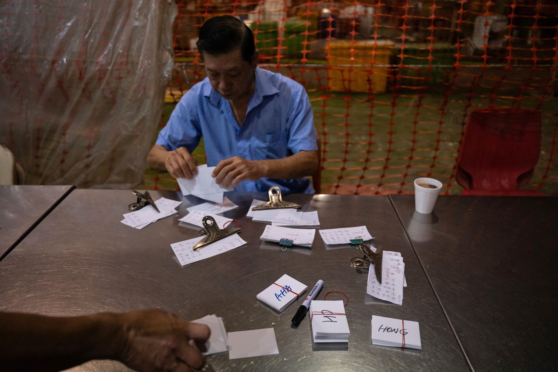 A worker sorting out paper labels that indicate the types of fish displayed at Lian Yak Fish Merchant.