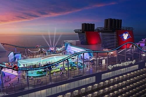 A cruise ship deck at sunset with a rollercoaster. Disney funnels are visible in the background.