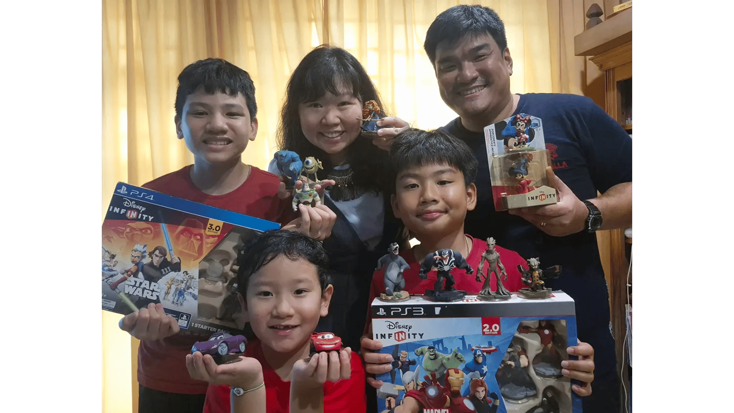 Family of five smiling and holding Disney Infinity game boxes and figures.