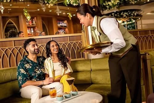 A server brings drinks to a smiling couple in a luxurious lounge.