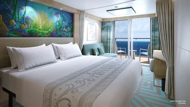 Cruise ship cabin with a bed, The Little Mermaid mural, sofa, and ocean view balcony.