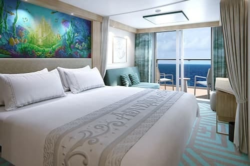 Spacious cruise cabin with a large bed, vibrant underwater mural, and ocean-view balcony.