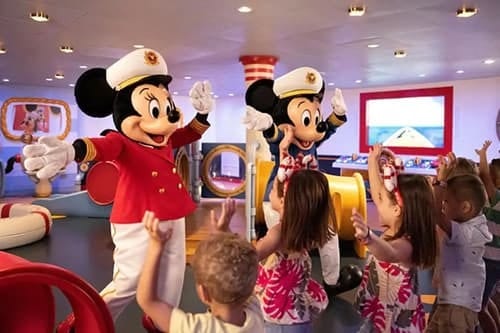 Captain Mickey and Minnie Mouse wave to excited children in a colorful indoor setting.