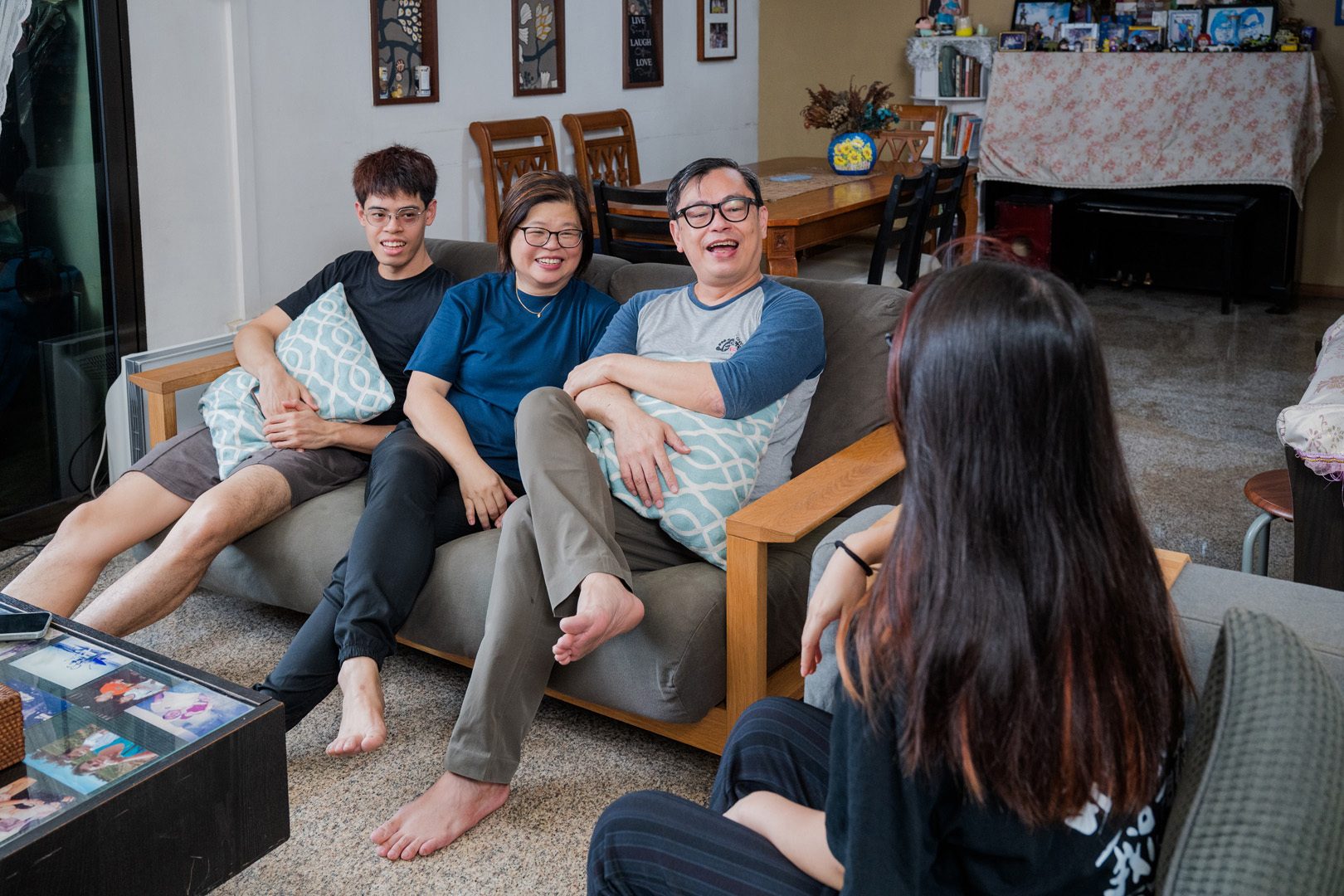 A family of four laughing together on couches in their living room, enjoying a casual moment.