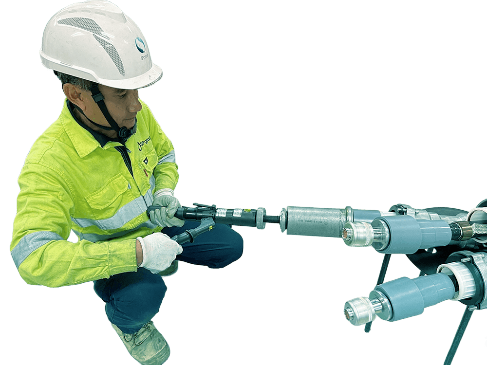 A worker in safety gear connecting specialized cables and equipment, demonstrating maintenance or installation.