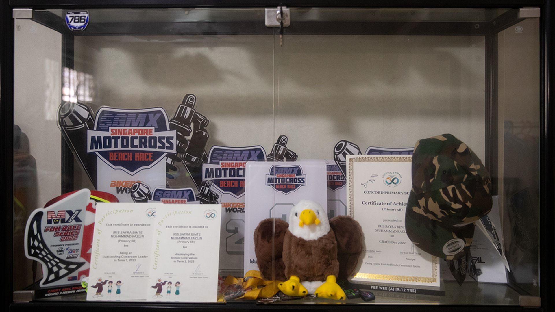 A display cabinet showcasing the children’s motocross and academic achievements at the family’s flat.
