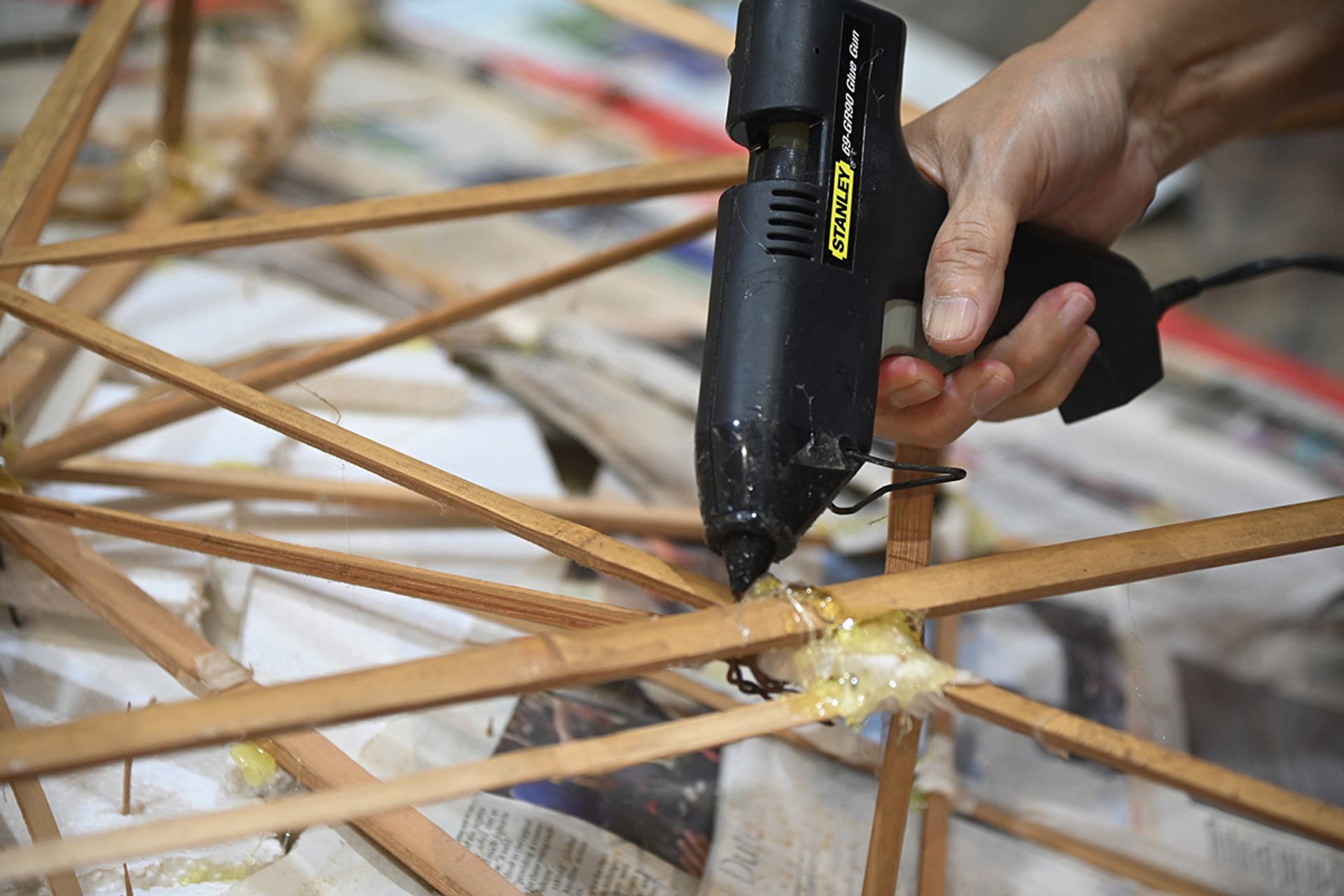 Mr Wong using hot glue to reinforce the joints of the bamboo stick scaffold of the Seven Sisters basin he crafted back in 2019.