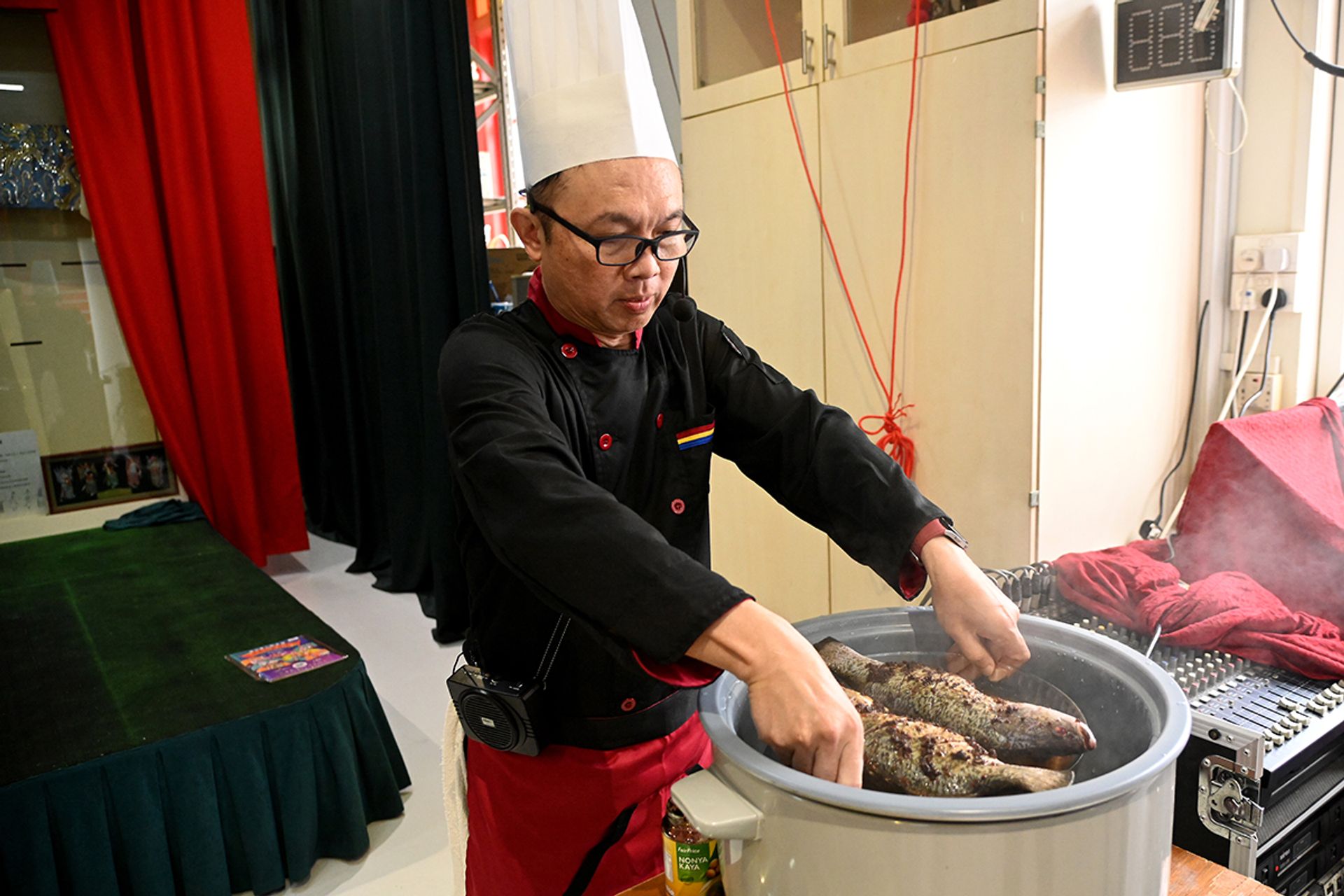 Mr Wilfred Aw Yeong placing two sea basses marinated with chilli biscuits into a steamer during his cooking demonstration on July 16.
