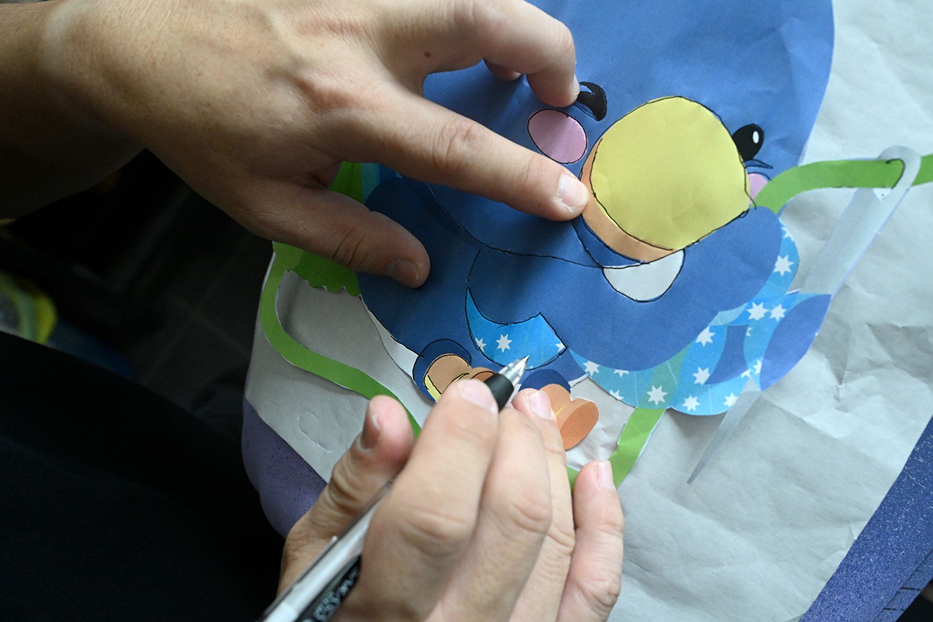 Mr Yeo tracing the outline of QiQi, the Qixi Fest magpie mascot, on his lanterns.