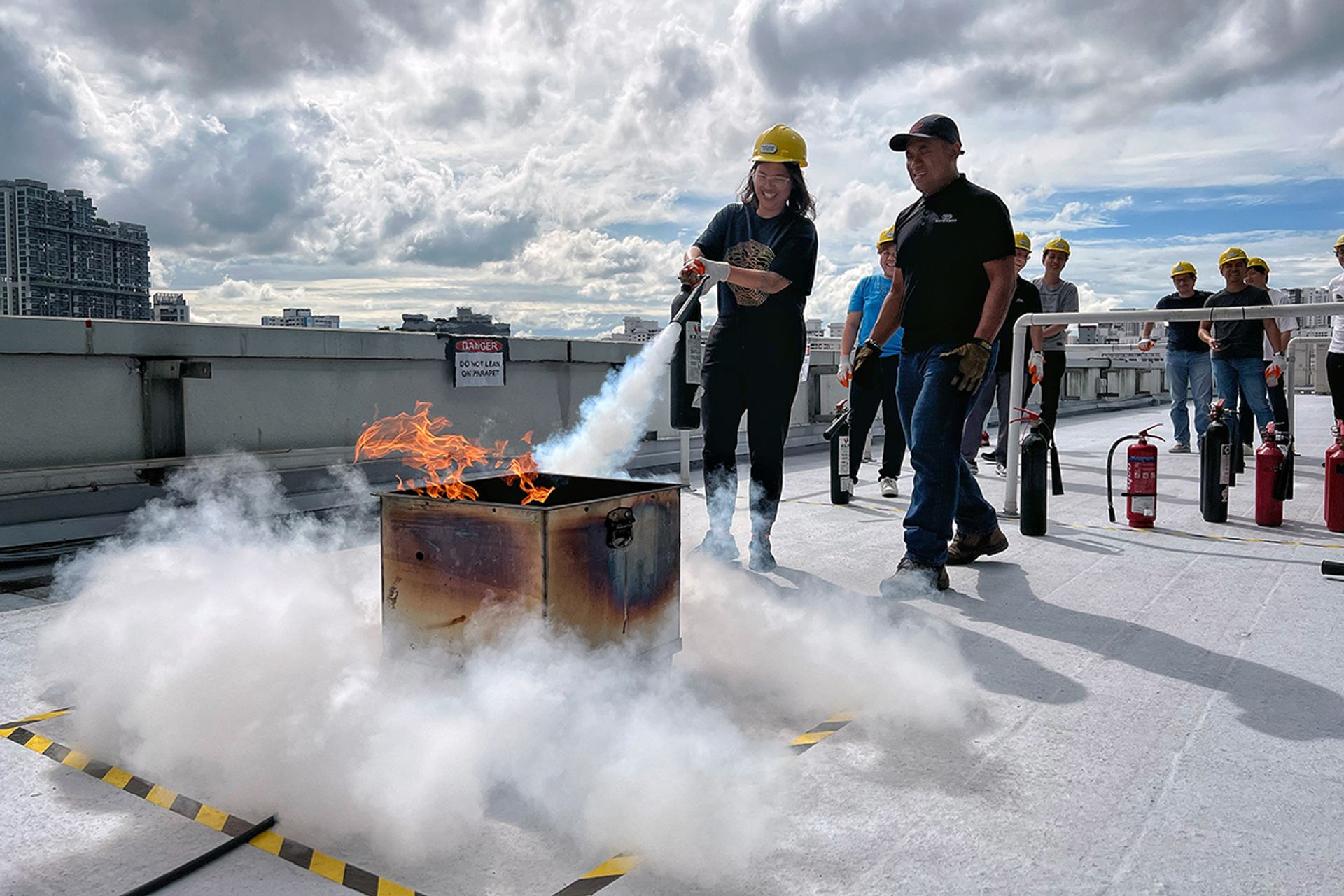 Ms Tan Wanqi (left), a 34-year-old cyber-security engineer, extinguishing a fire under the watchful eye of chief instructor Mohammad Faizal Zainal (right), 45, during a practical training session for fire marshals at CJ Logistics Building in Jurong East on July 1.
