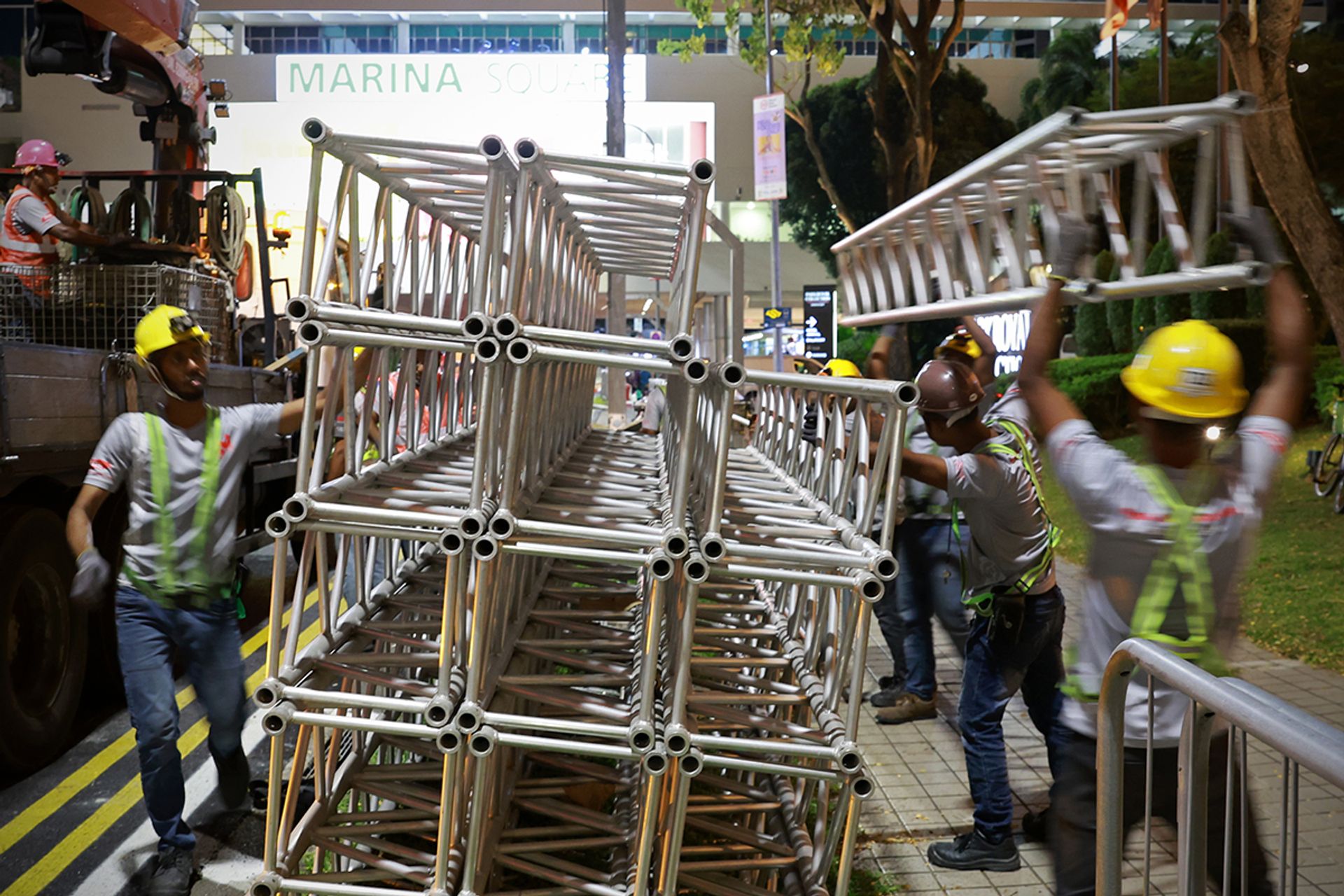 Workers unloading light trusses to line them up for installation in Raffles Boulevard on July 25.