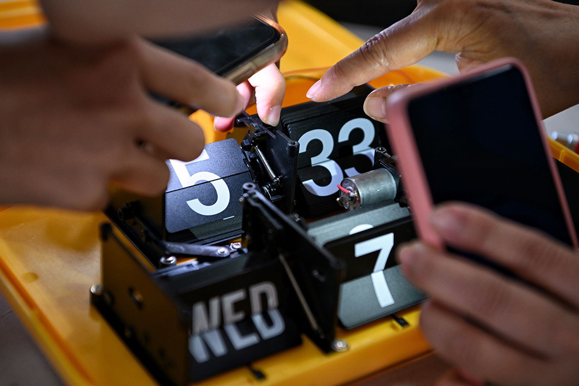 Torchlight from their mobile phones are used to have a clearer look at the clock mechanism during a Repair Kopitiam session.