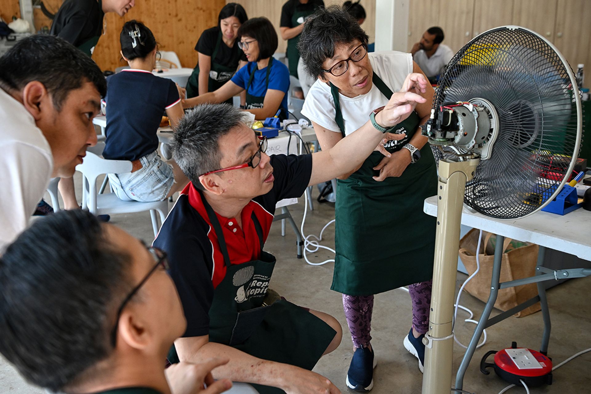 Repair Kopitiam veteran coach Andy Lee, 57, information management director, and trainee coach Jeanette Tan (right) inspecting the parts of a standing fan that was unable to oscillate. ST PHOTO: KUA CHEE SIONG