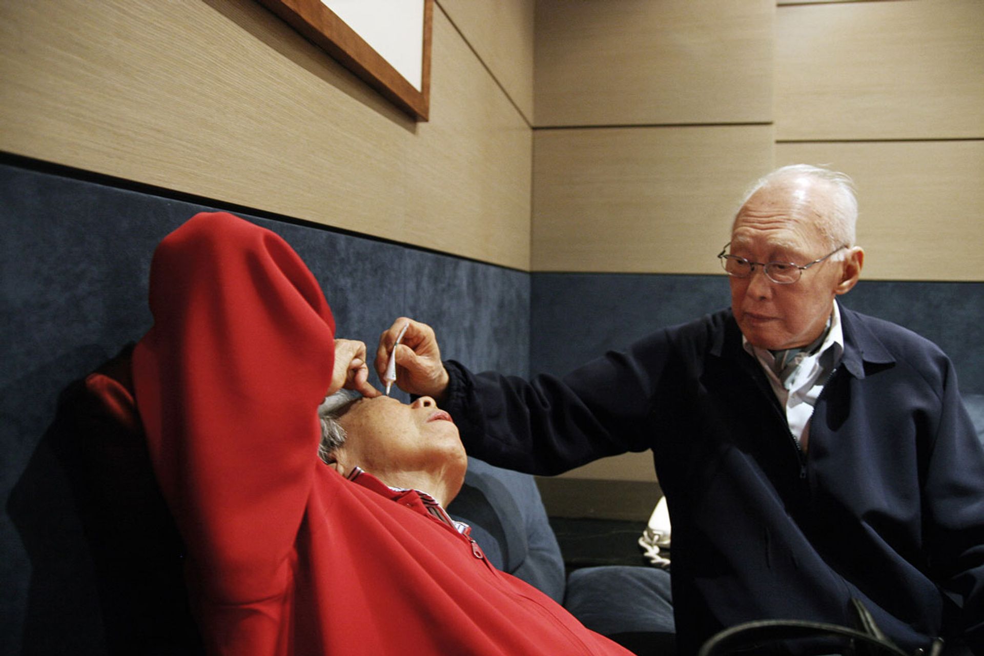 Better together: Mr Lee putting eye drops for his wife in an airport waiting room in Milan on May 16, 2007. Photo: Li Xiuqi