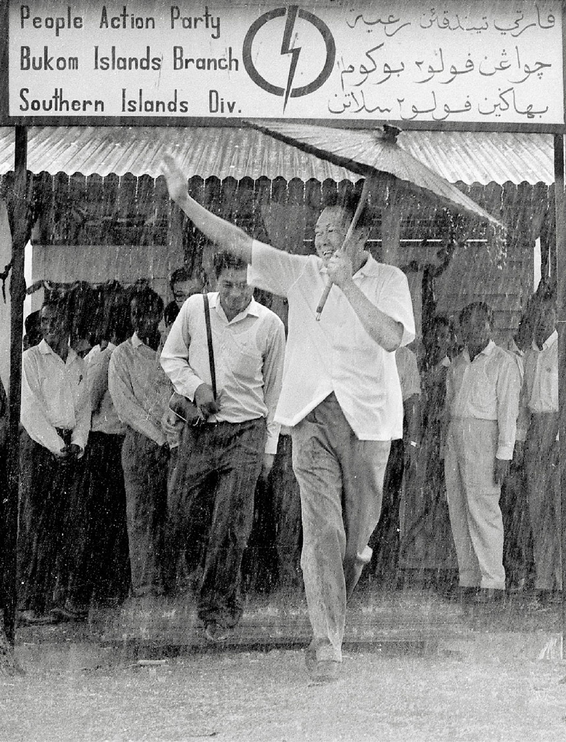 With a small umbrella in hand, Mr Lee braved the rain at the opening of the new People’s Action Party branch on Pulau Bukom Kechil, part of the Southern Islands, on April 3, 1966. It was set up to strengthen local grassroots. ST Photo: Mak Kian Seng