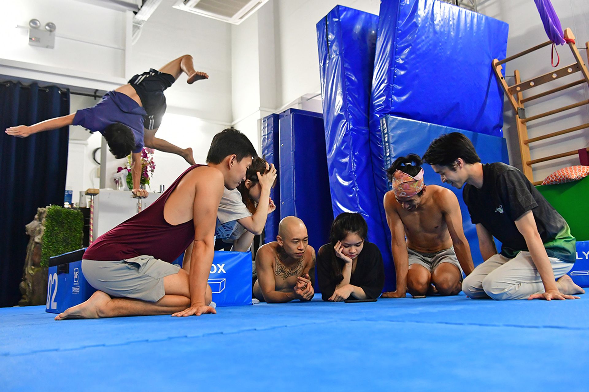 The Circus of Altrades crew, including creative director Beverly Wan (centre), watching videos of their rehearsals during one of their many night practice sessions in a studio in Ubi. Meanwhile, Mr Foo Ping practises his one-arm handstand in the background.