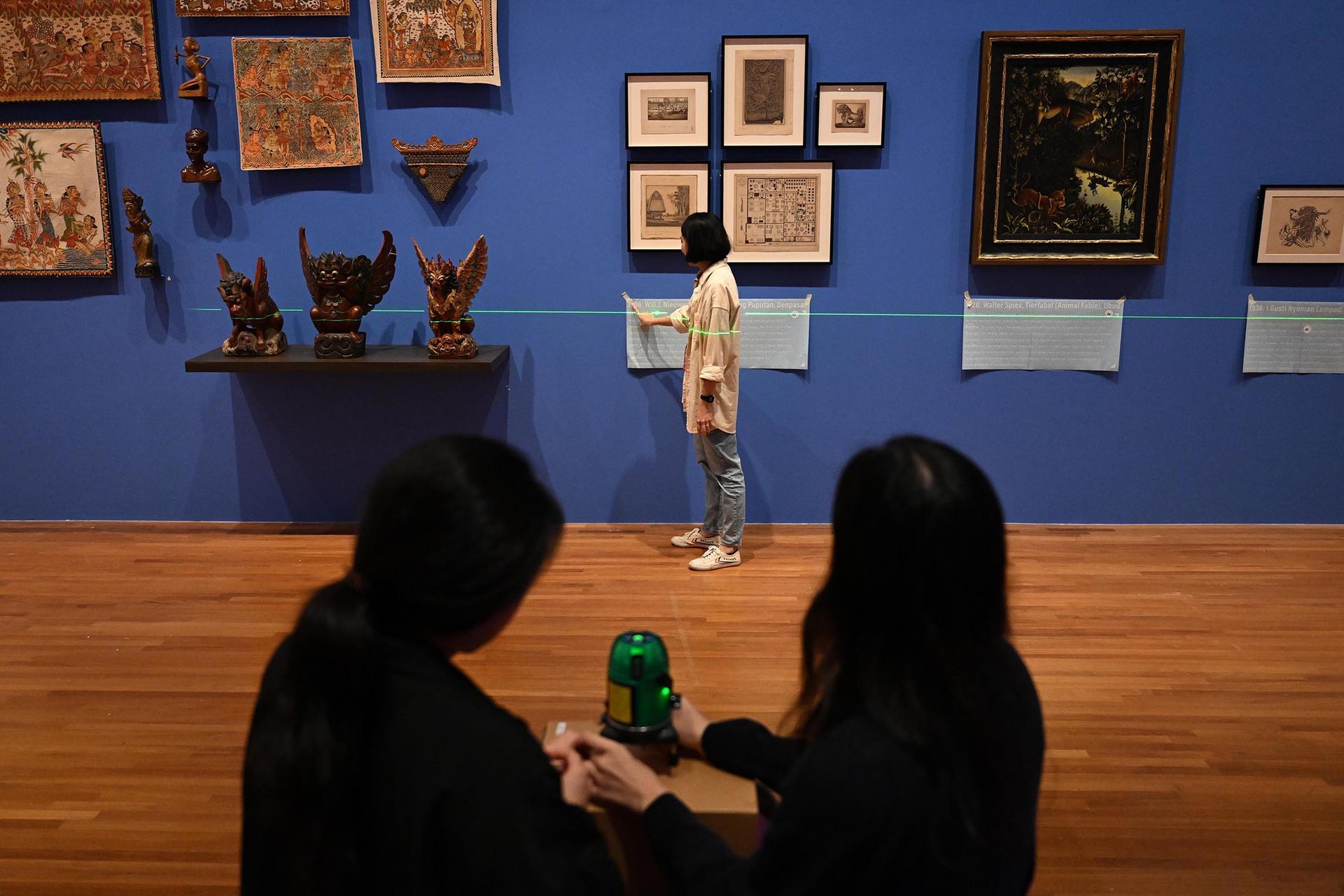 Curator Teo Hui Min, 33,  checks the laser levelling device to ensure that the text panels are aligned with the paintings.