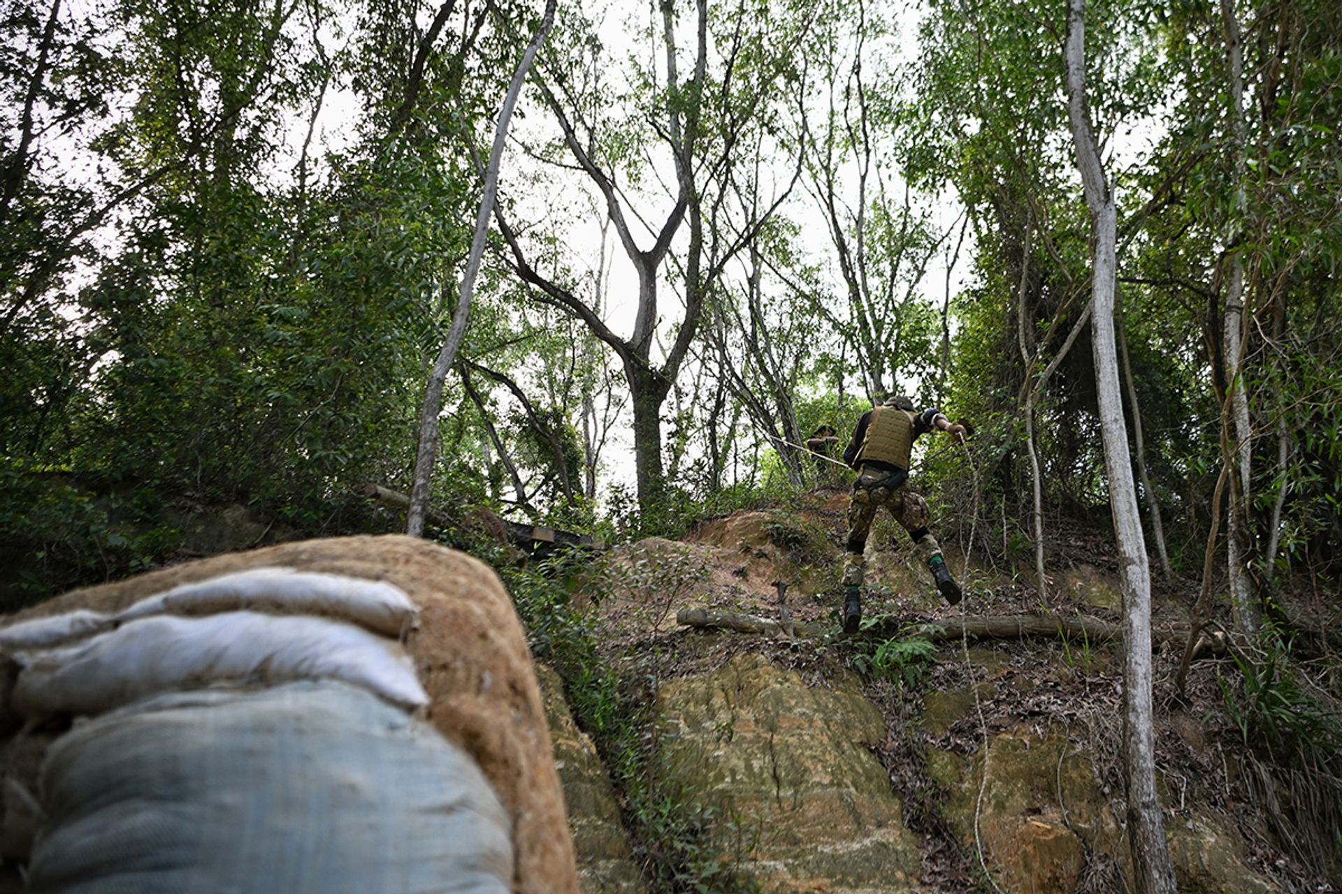 Mr Mohd Wira smoothly descends the steep slope at Tampines Quarry, confidently showcasing his adept rappelling skills. Meanwhile, the rest of his siblings watch on, observing the controlled descent.
