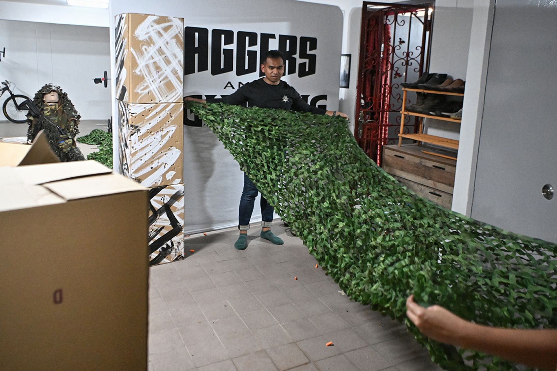 After training, family friend Muhd Yasser assists in folding a camouflage net. The group ensures the lift lobby is back to its usual state.