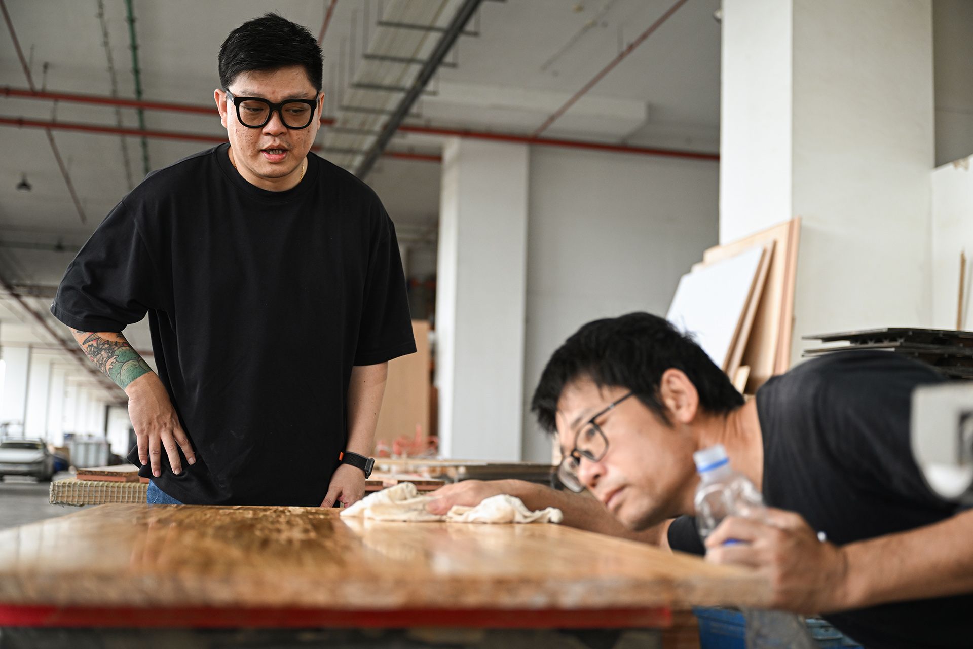 Mr Justin Lee inspecting an end product as Mr Zheng Liangqi finishes the surface with lacquer.