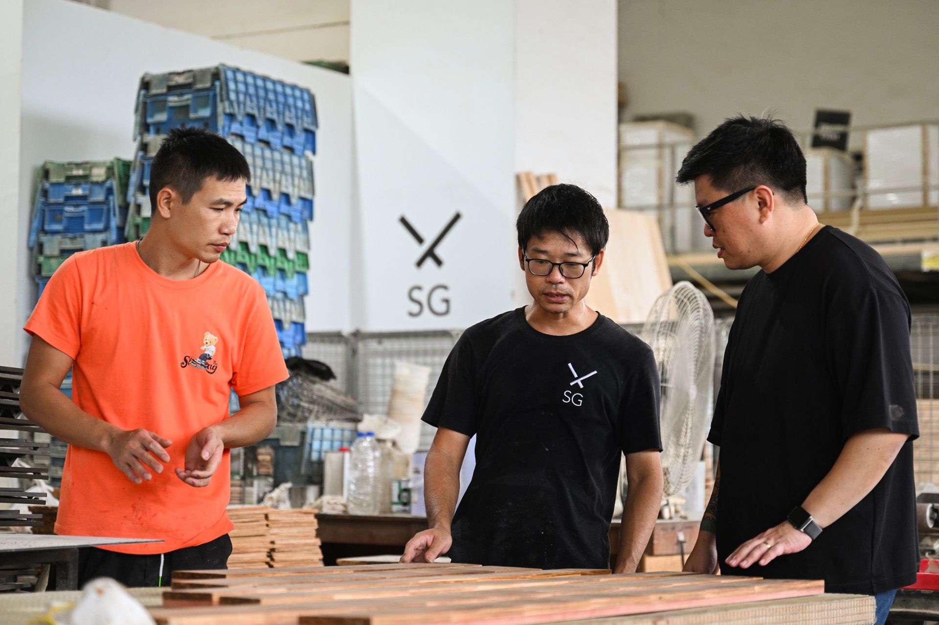 (From right) Mr Justin Lee speaking to his employees Zheng Liangqi and Zhen Huiwu at the ChopValue microfactory.