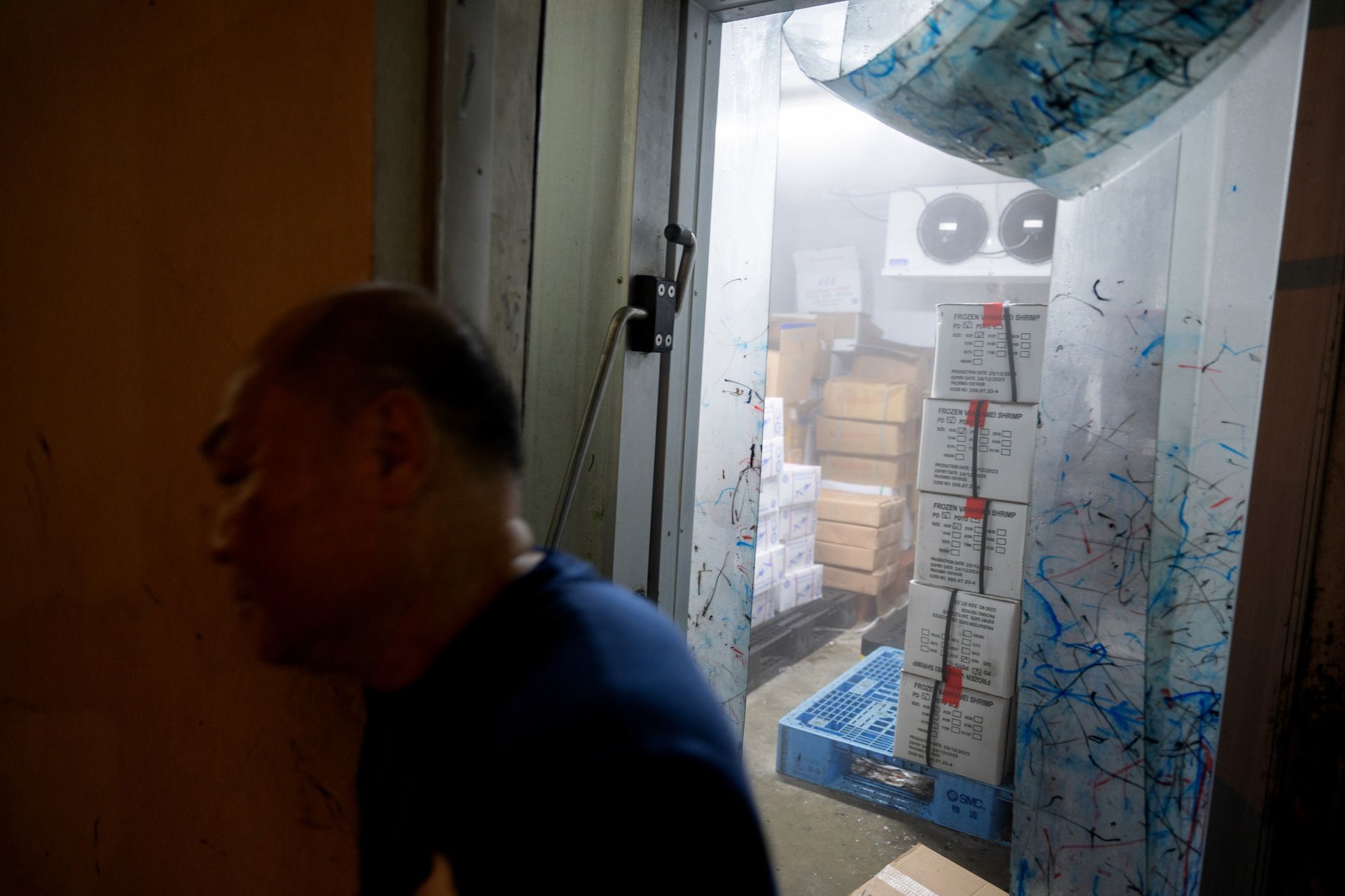 A worker coming out of a cold room, which is used to store frozen food.