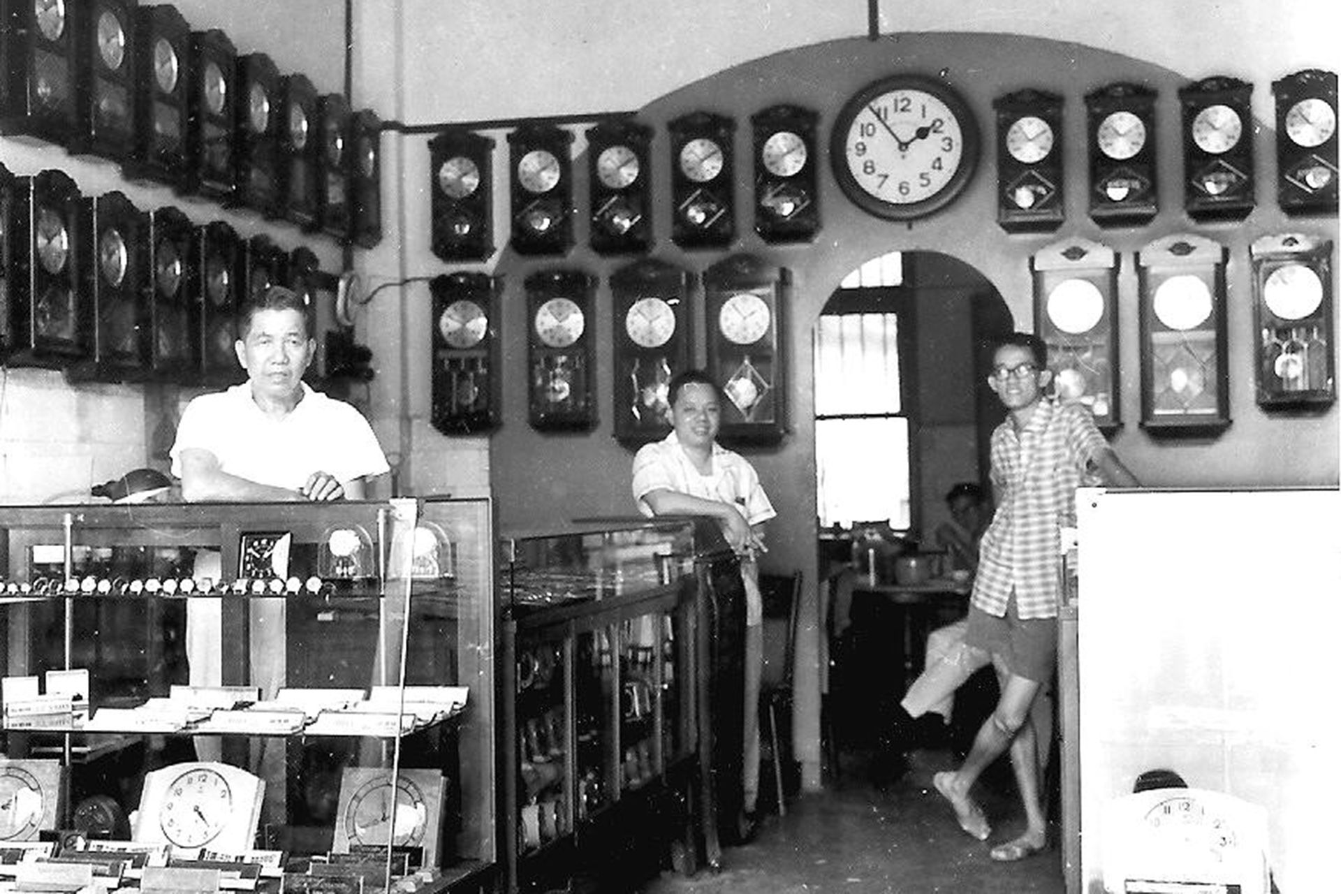 (From left)  Mr Mun Sah (Mr Mun Chor Weng’s father), Mr Kan Hong Keen (father’s assistant), and Mr Mun Chor Koon (eldest brother), in the clock shop. Mr Mun Chor Weng is partially blocked at the back, having lunch after school in the 1950s. PHOTO: COURTESY OF MUN CHOR SENG