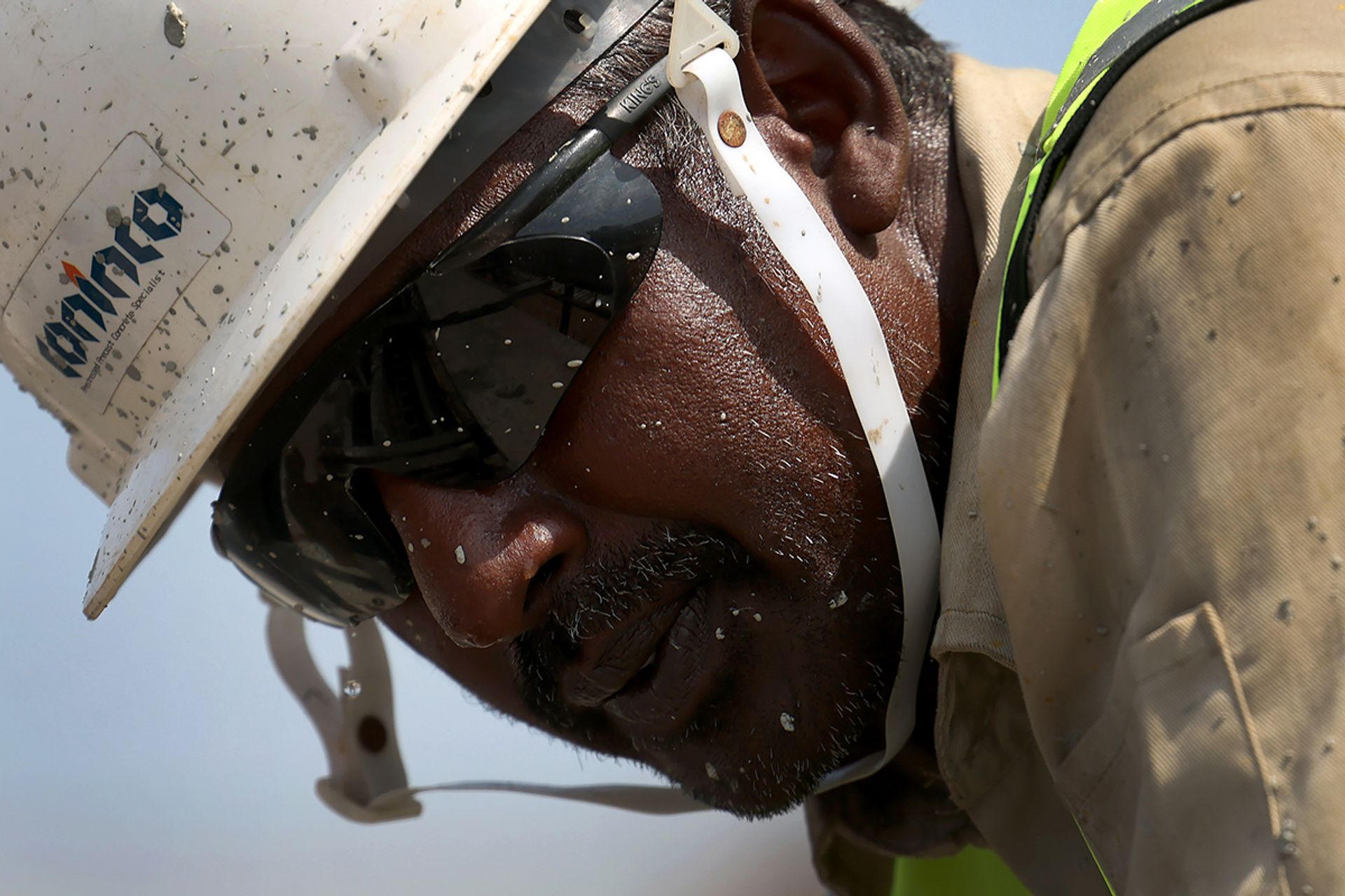 A worker’s clothes and helmet are speckled with concrete as he works at the Coninco precast yard on Feb 6.