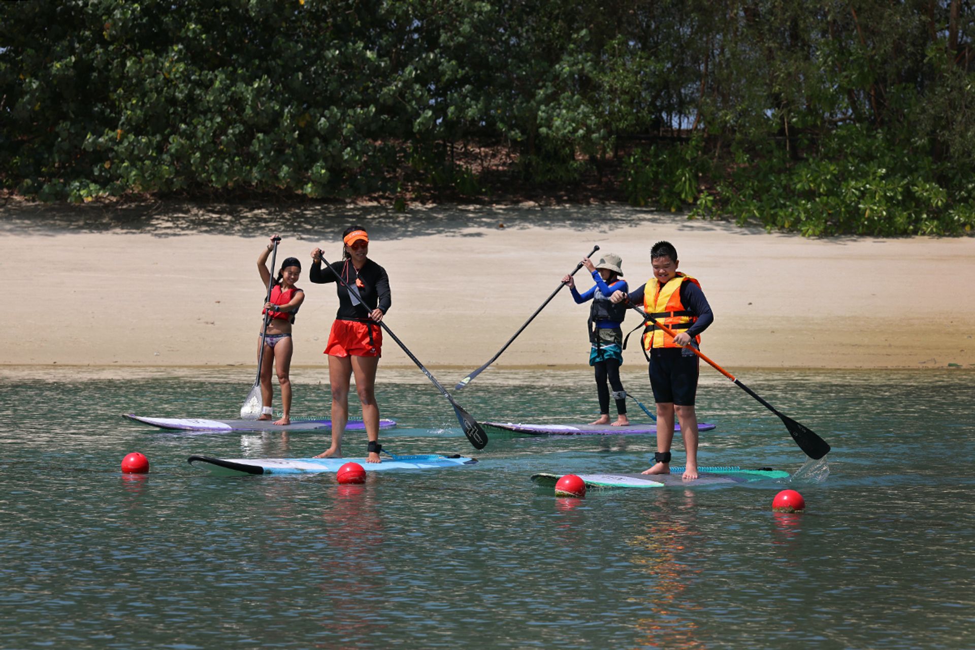 Jozen Lum (second from right) stand-up paddleboarding alongside Lim Zi Keat (right), 12, who has autism, and water sports coaches Gracie Teo (left) and Lilian Tong, 33, at Siloso Beach, Sentosa, in March.