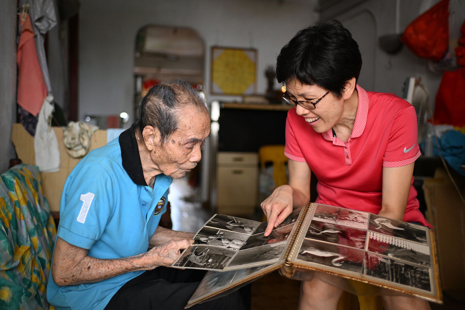 Mr Lee Wong, 91, showing Ms Yip Lai Kuen photos that he took in his younger days as a freelance photographer.