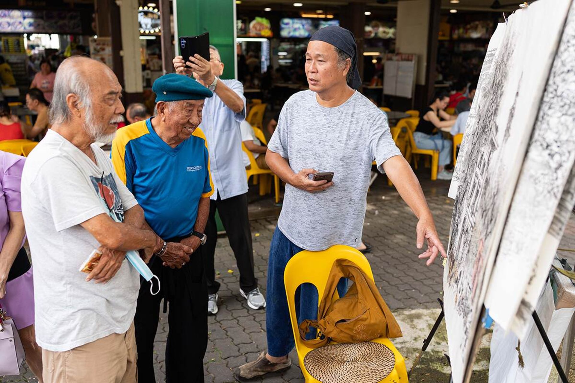 (From left) Mr Lau Puay Hua, 79, and Mr Loke admiring the artwork of Mr Tung Yue Nang, 65, at a coffee shop at Clementi Avenue 2. This is one of the Sunday gatherings of artists from the Clementi Coffee Shop Group, in which they critique each other's artwork.