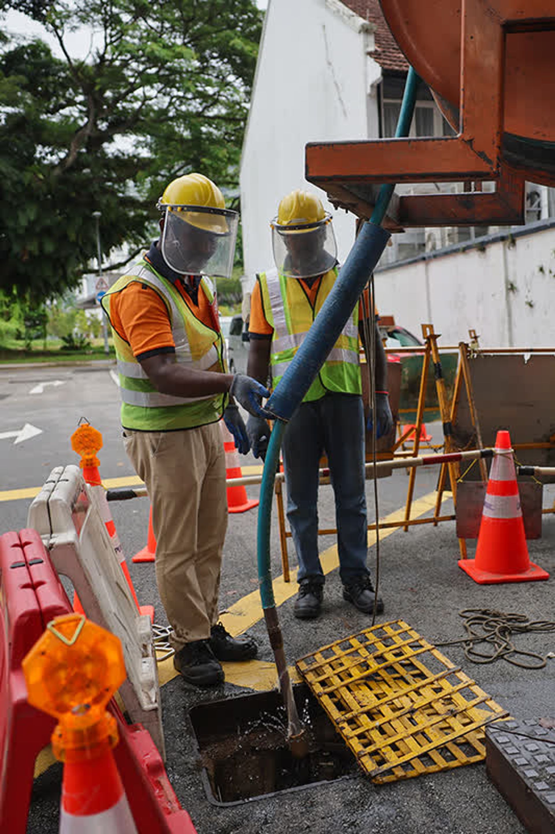 Sewerage maintenance officers setting up the Combi, a high-pressure water jet, for cleaning the sewers.