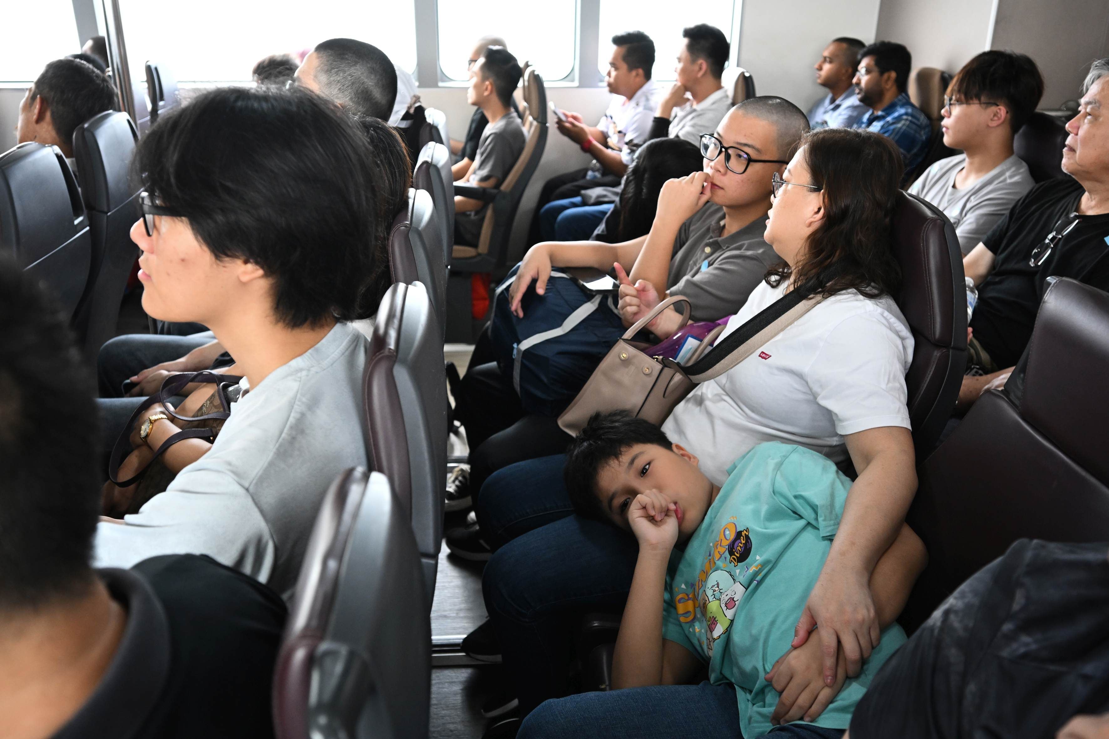 People of various ages and races on a ferry going towards Pulau Tekong.