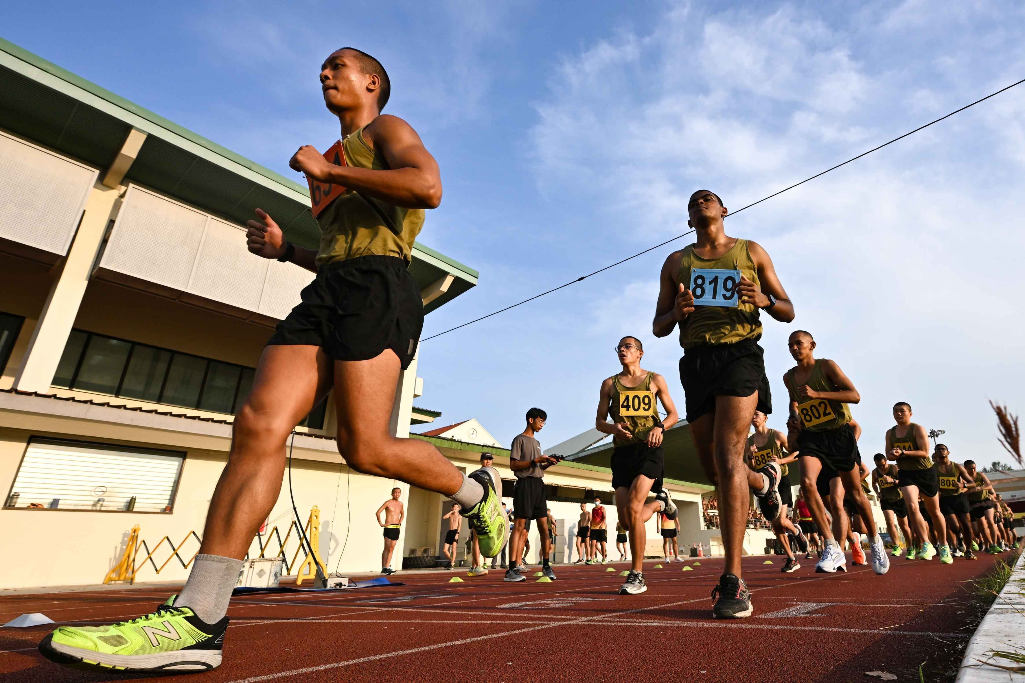 A group of men run around a track during a physical test at the Basic Military Training Centre on Pulau Tekong.