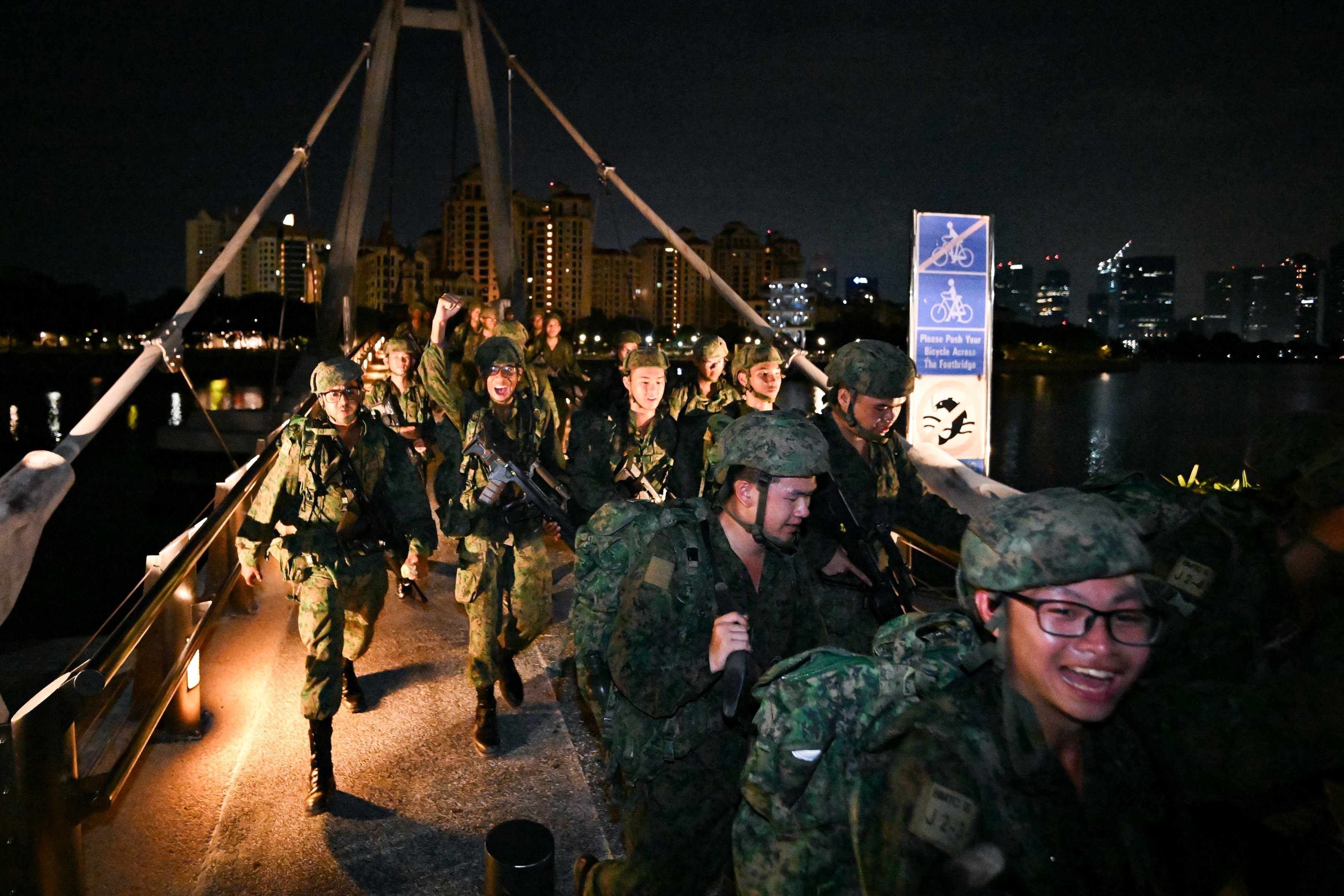 Men in the Singapore army uniform walk across the Tanjong Rhu Suspension Footbridge