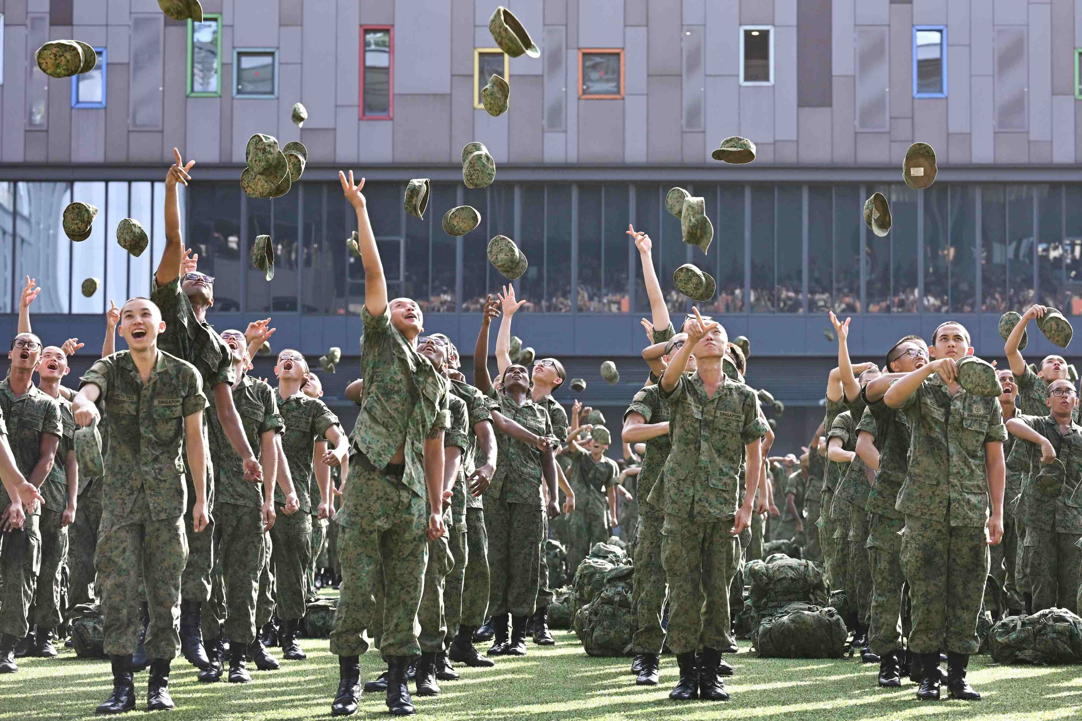 Men in the Singapore army uniform toss their jockey caps during the Basic Military Training Graduation Parade at Our Tampines Hub