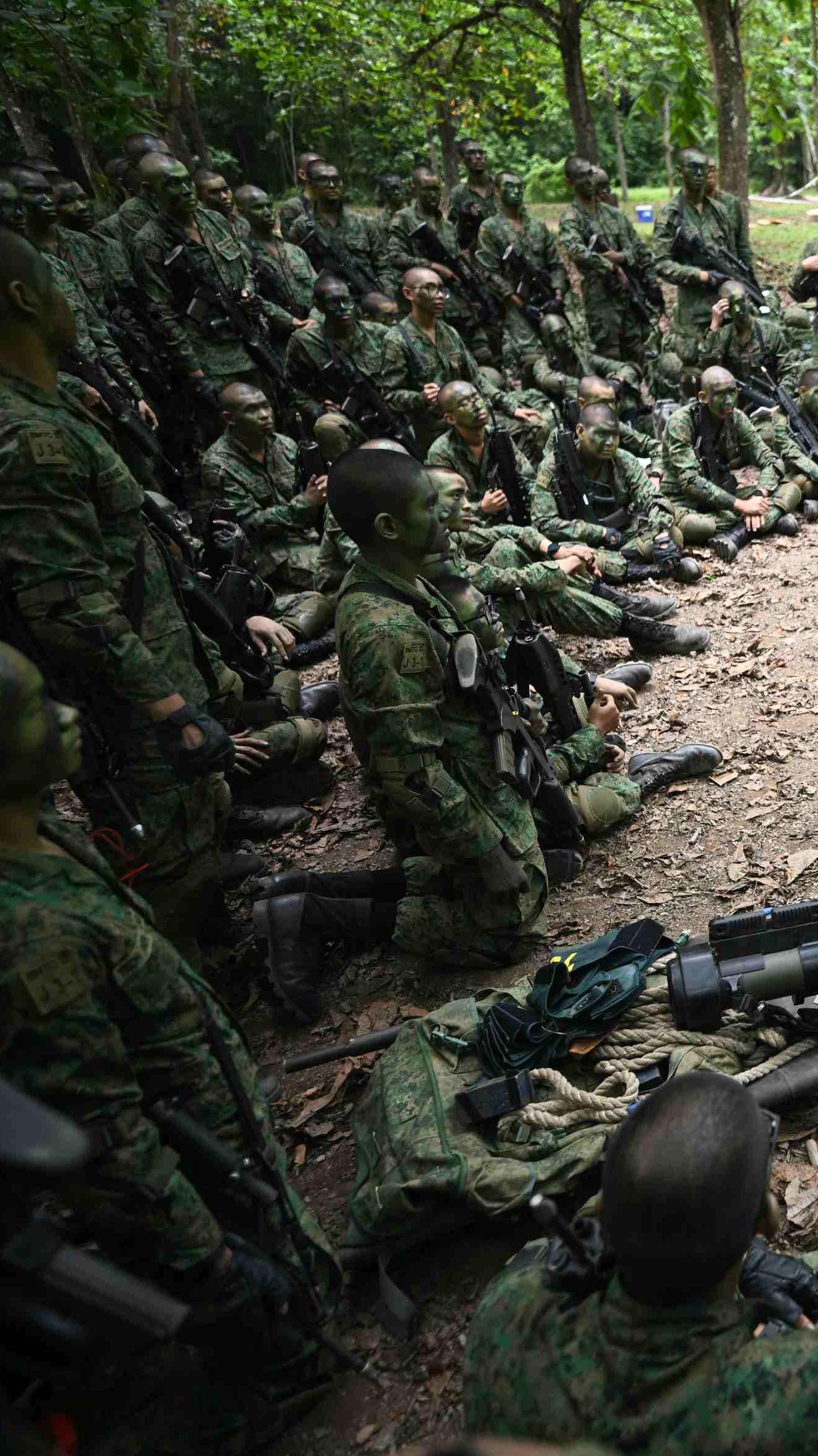 Men in the Singapore army uniform gather around for a discussion