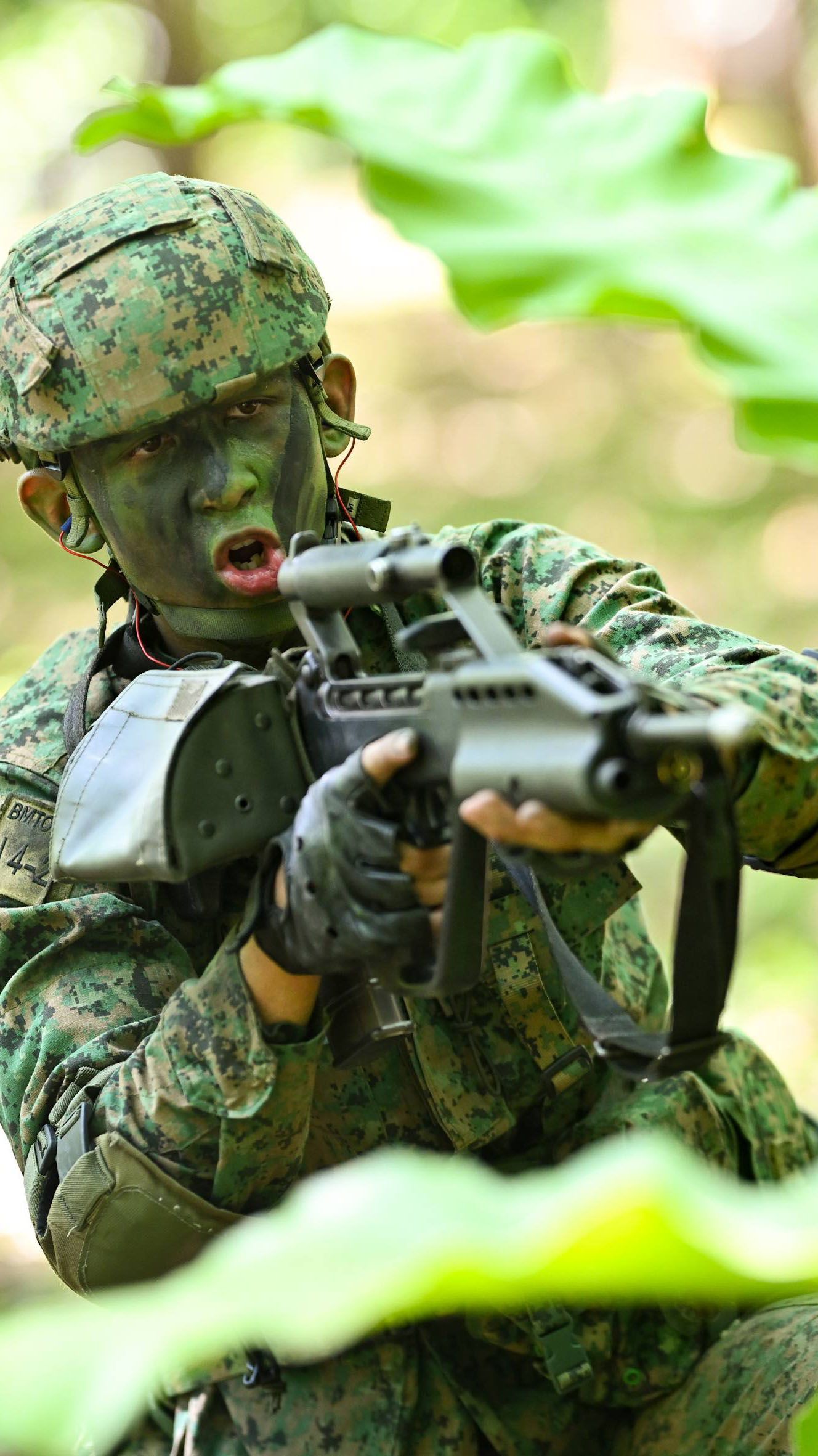 A man in a Singapore army uniform points his rifle during an army exercise