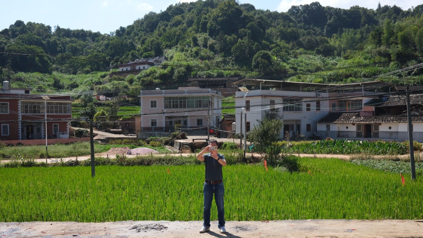 A participant on a *xun gen* tour taking photos of Zhiyang village in Anxi, which has become more developed over the past few years.