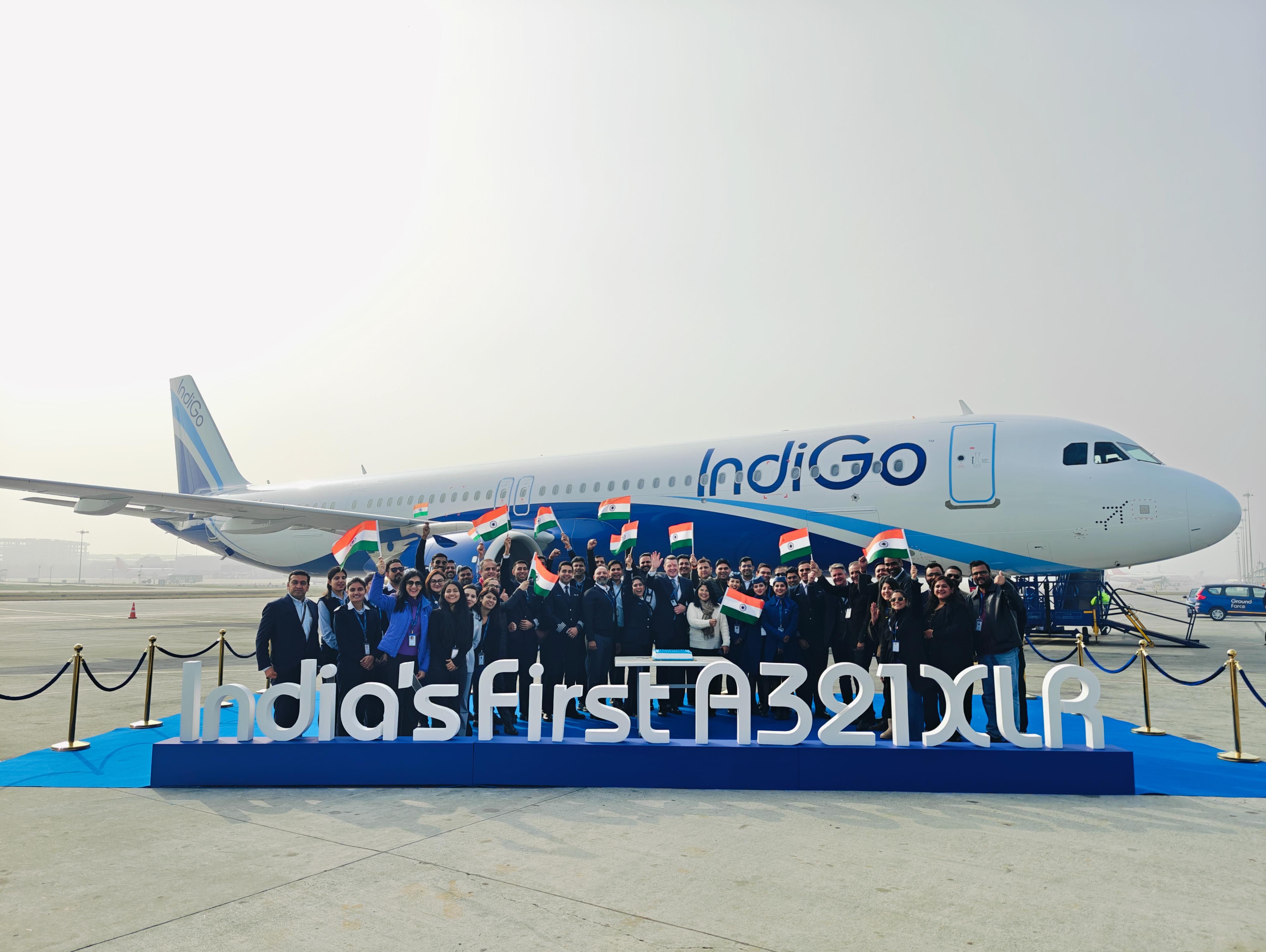A group photo of airline staff in front of the IndiGo Airbus A321XLR. In front of the group is a large display sign that says “India’s first A321XLR”.