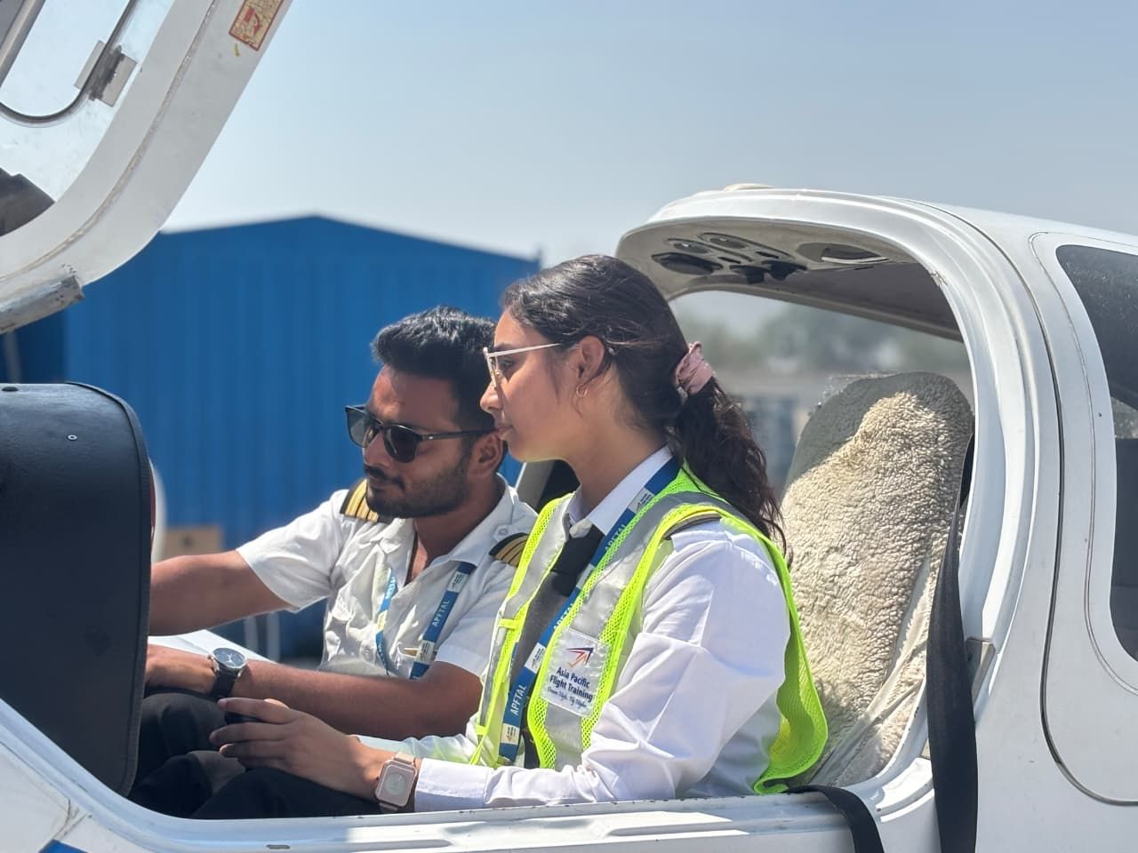 A woman pilot trainee sits in an aircraft going through a checklist with an instructor.