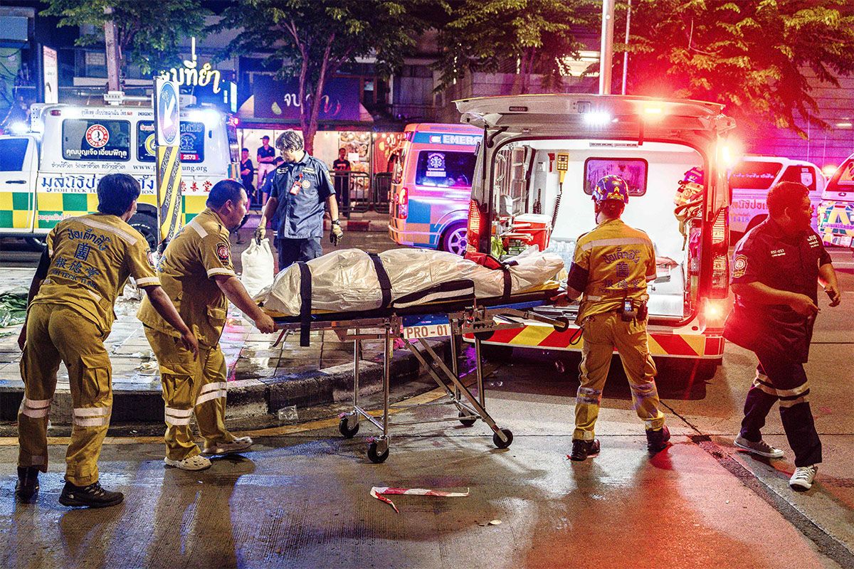 Emergency workers prepare to place the body of a victim into an ambulance after a fire at the Rong Beer Na Lat Phrao bar in Bangkok on July 13, 2026.