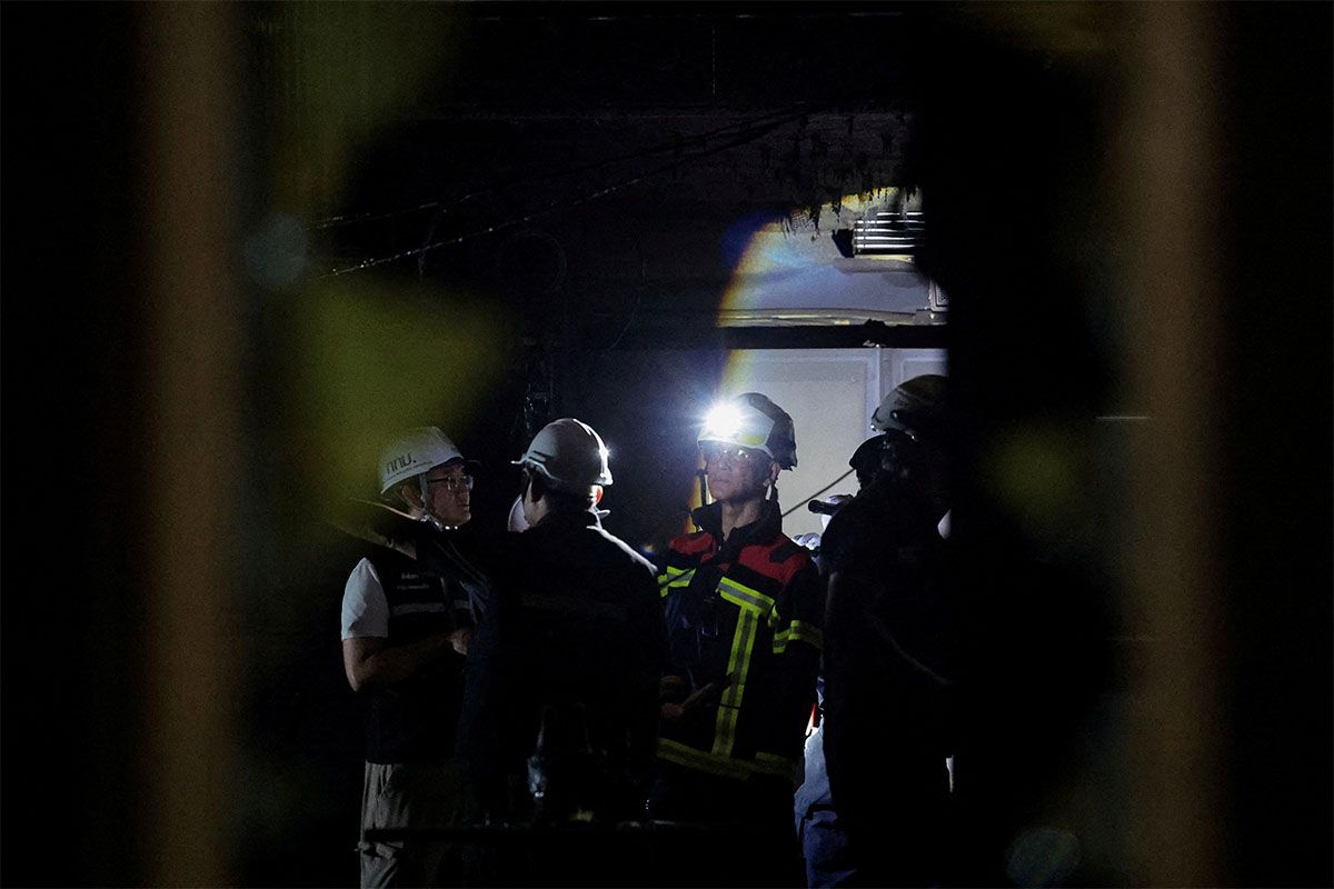 A firefighter wears a helmet with a torch, at the site of a deadly fire at a pub in Bangkok, Thailand, July 13, 2026.