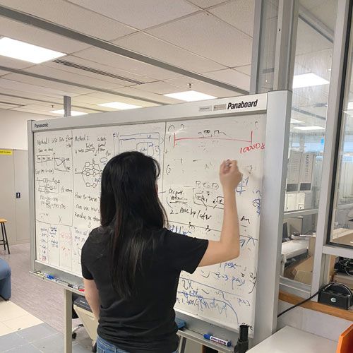 Ms Peksi writing on a whiteboard with a marker.